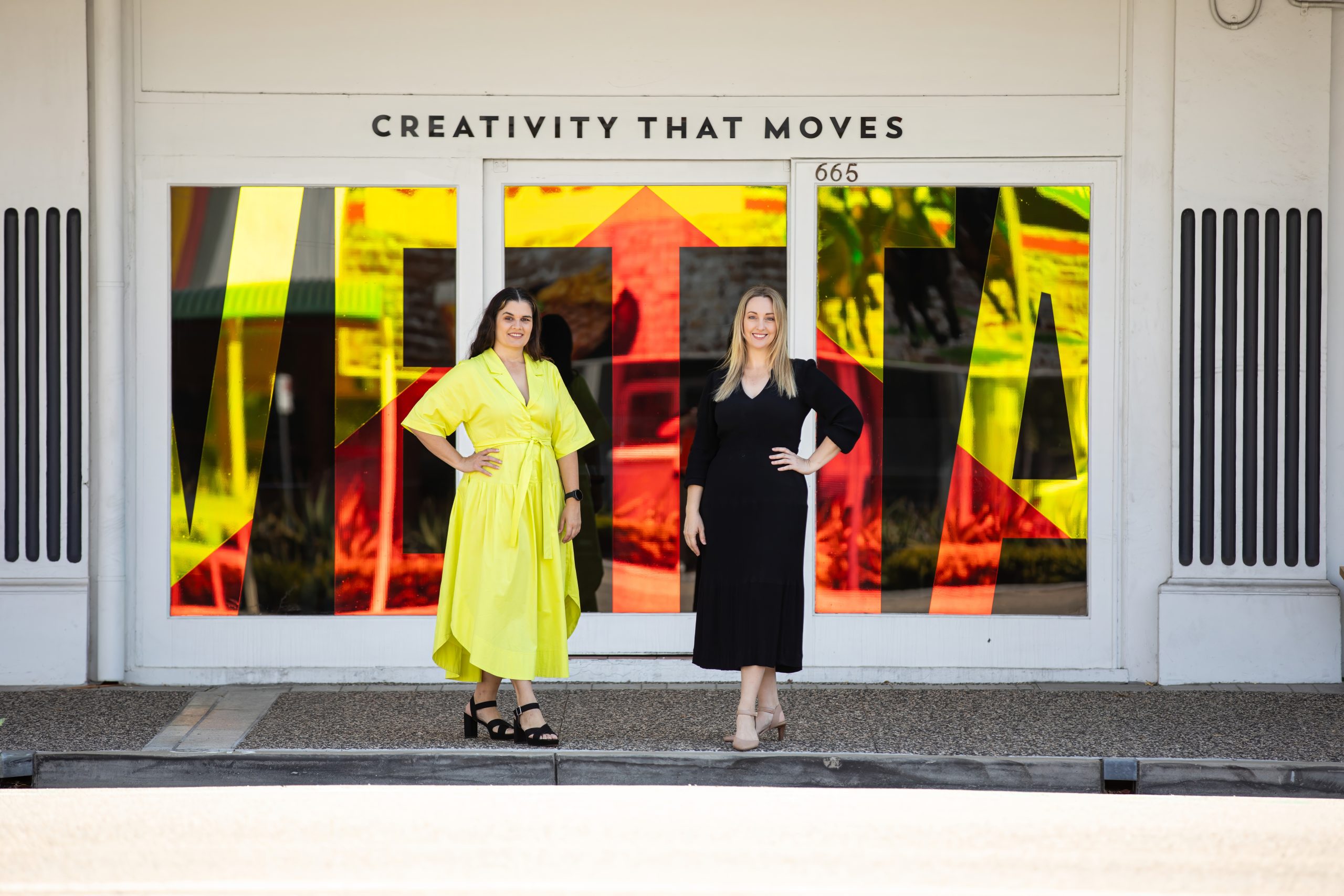 Directors Sarah and Kassia stand side by side in front of the Vetta Creative Office